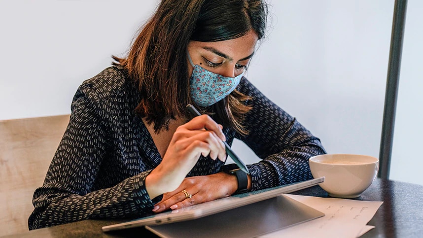Woman wearing a face mask and working on a tablet