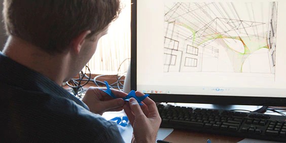 architect in front of computer with architectural model drawings